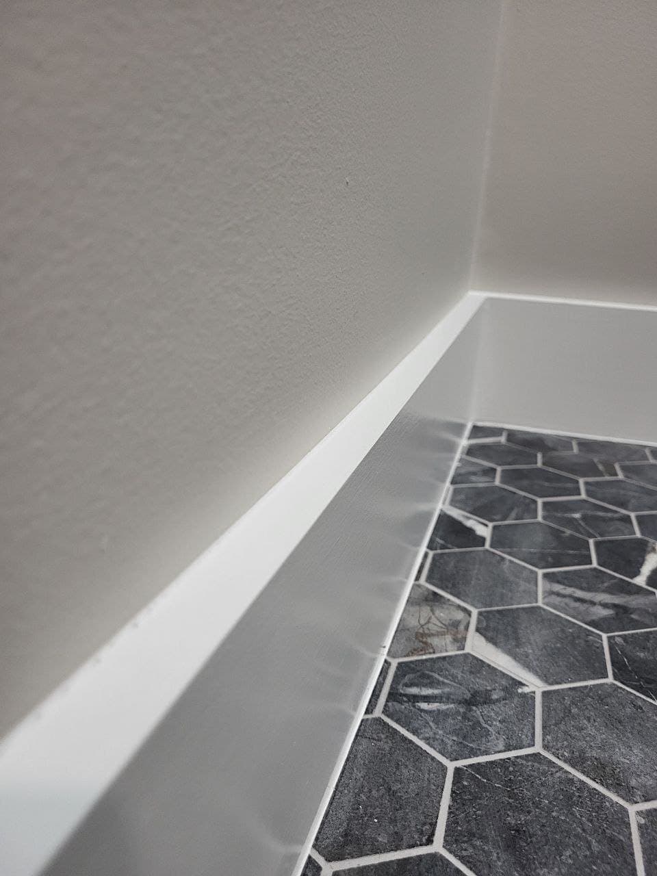 Baseboard trim detail over hex marble tile floor