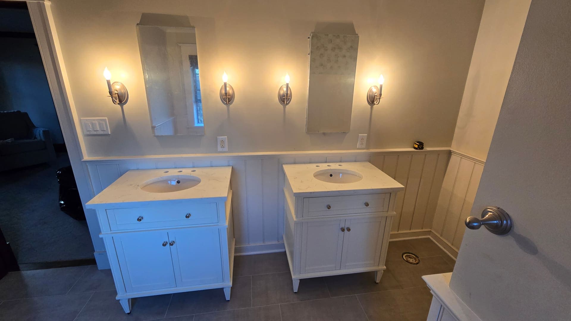 Twin white vanities with sconces and wainscoting during a bathroom remodel
