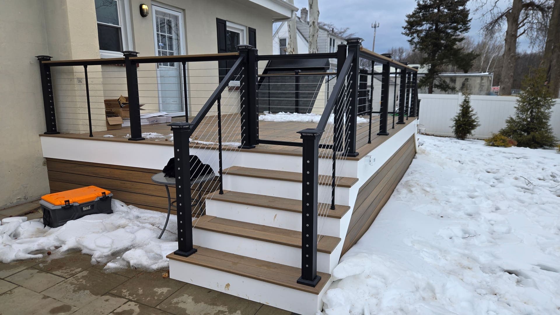 Composite deck with black cable railing and stairs built in winter