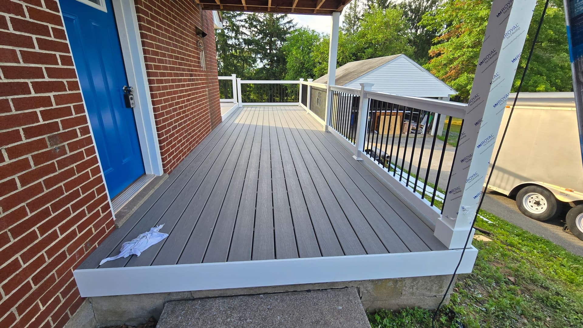 New gray composite deck with white vinyl railing at a blue front door