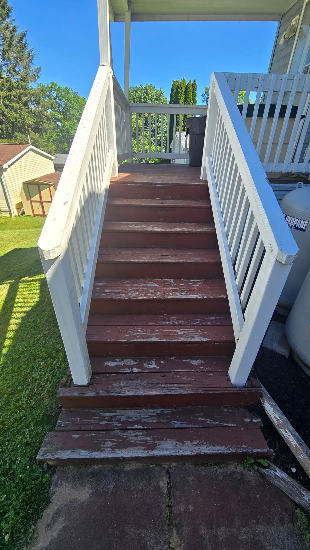 Old deck steps with peeling red paint before rebuild
