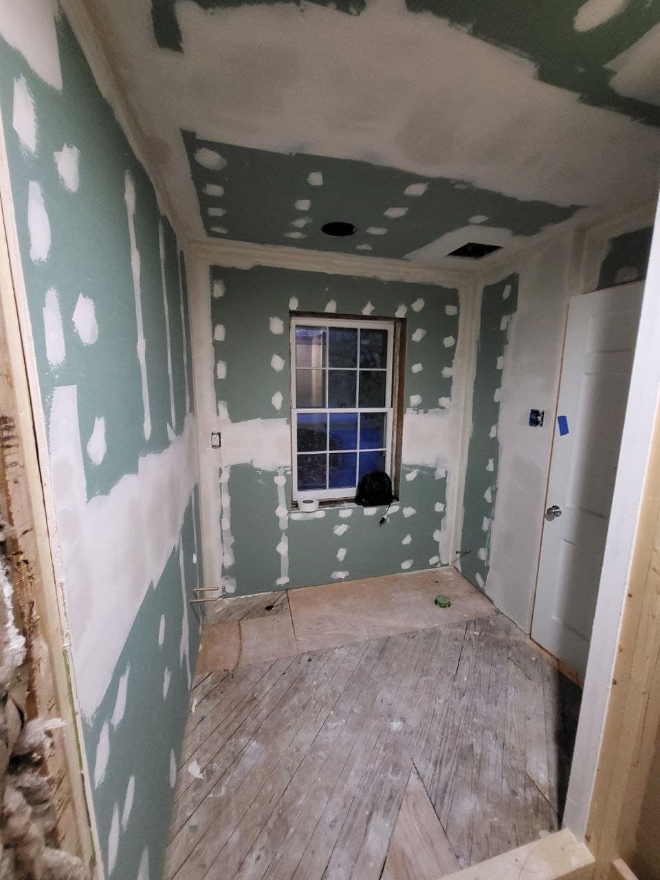 Room fully hung with green board drywall, seams taped