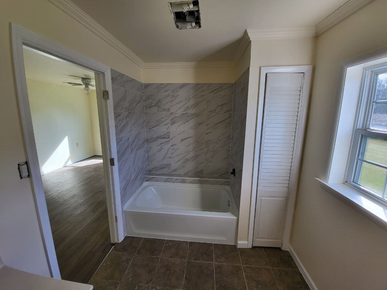 New tub with marble look tile surround and tiled floor